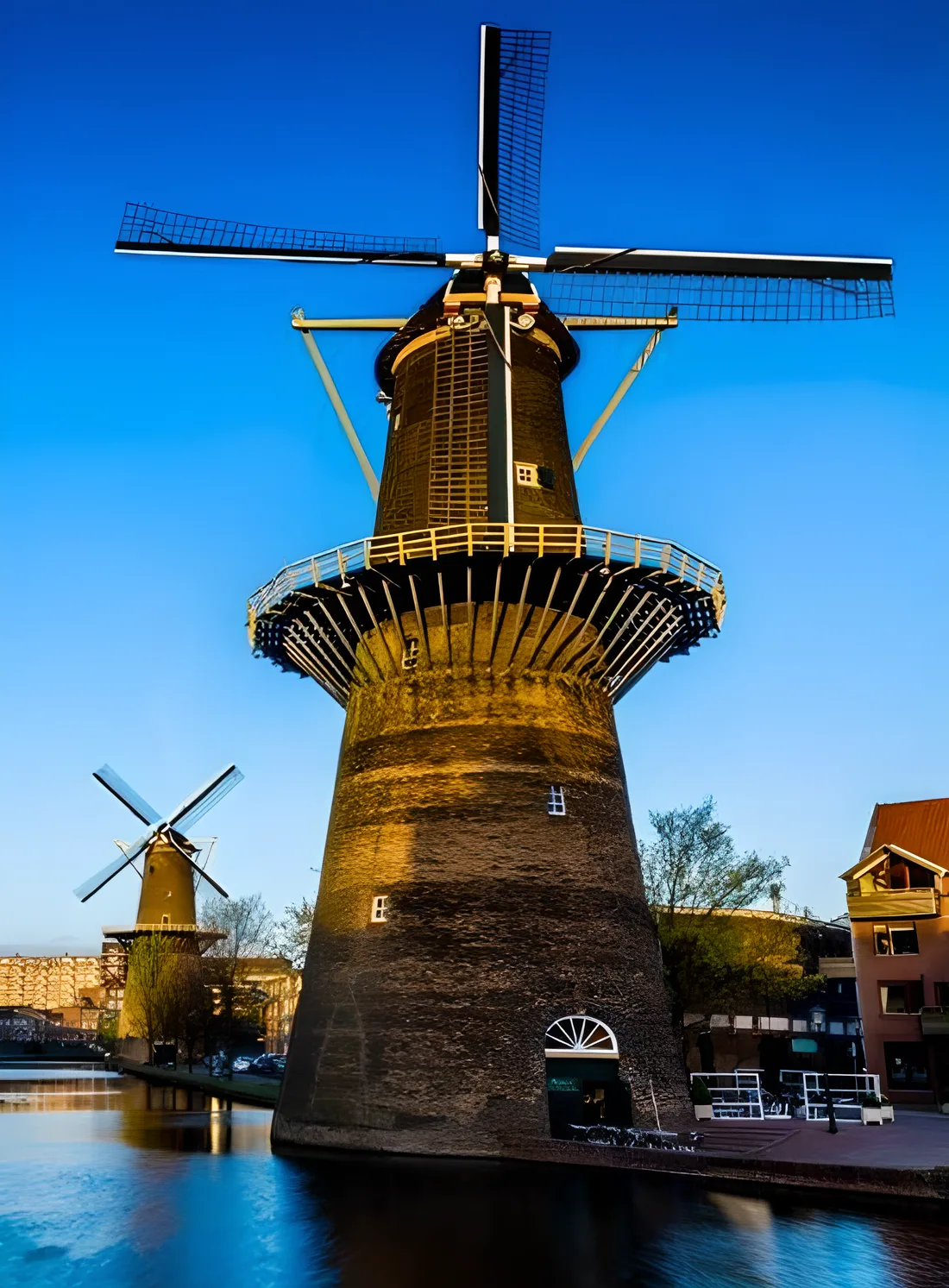 Molen De Noord aan de gracht, met de wieken tegen de avondlucht