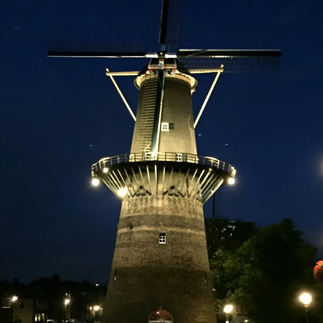 Molen De Noord 's avonds verlicht, de balie en de wieken uitgelicht tegen de donkerblauwe lucht