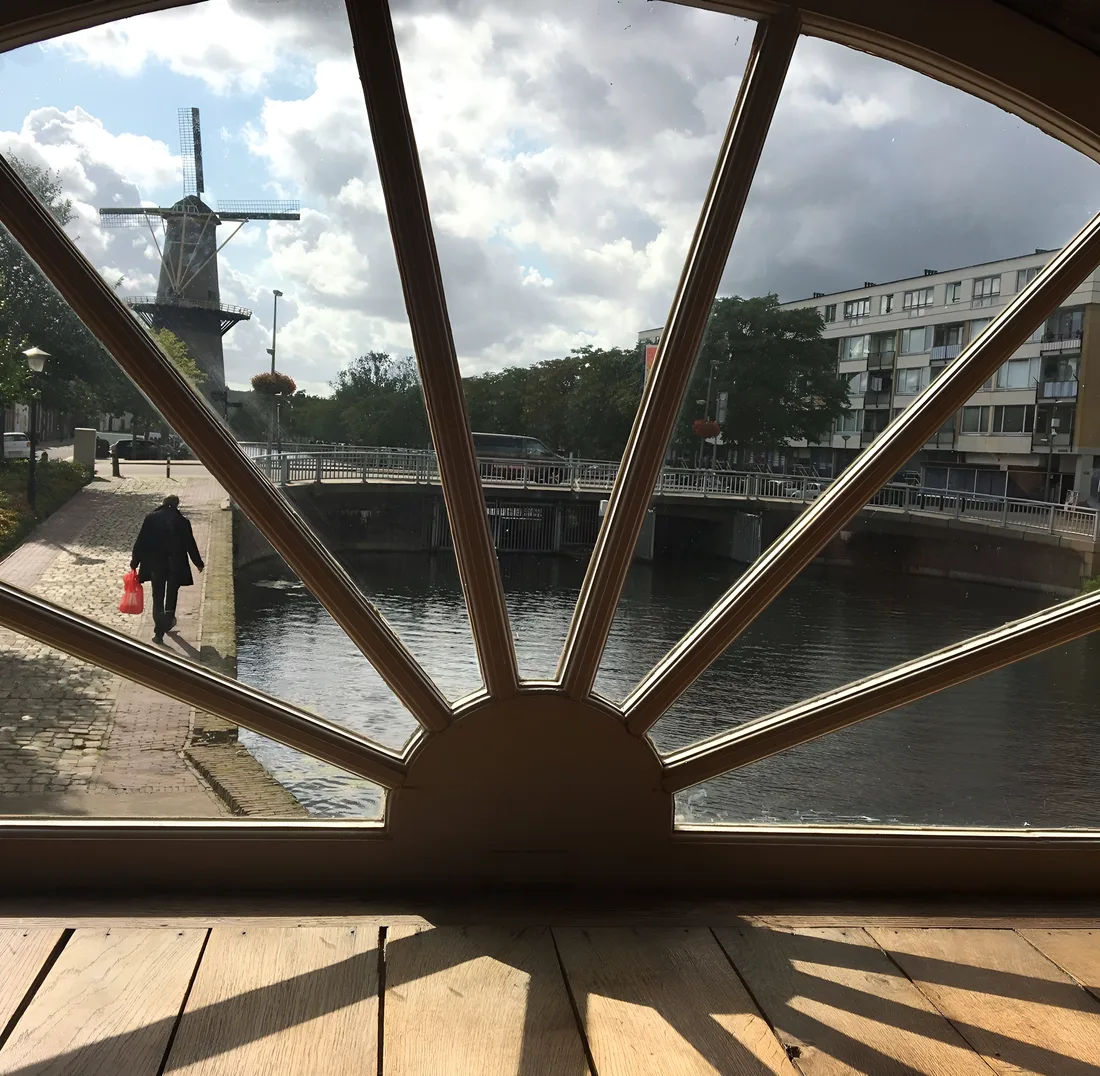 Uitzicht door het halfronde waaierraam van de molen over de Noordvest, met de brug en een tweede molen in de verte