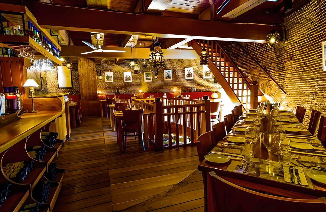 Lange gedekte tafel met wijnglazen en servetten langs de oude muur
